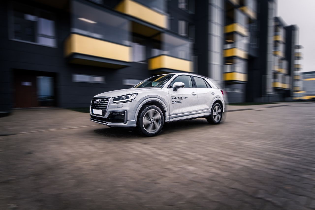 A dynamic shot of a modern Audi SUV speeding through a contemporary cityscape.